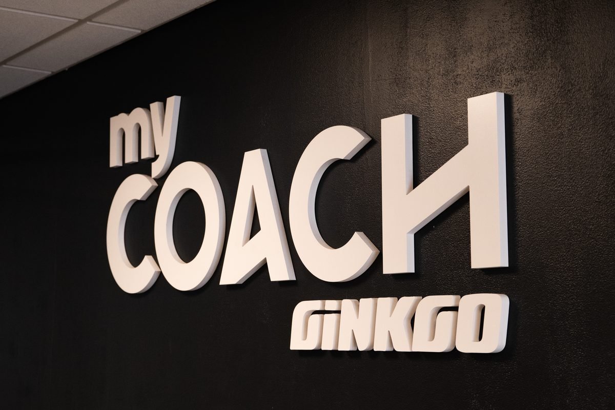 Logo My Coach Ginkgo en relief sur un mur noir : la marque que rejoint un franchisé.