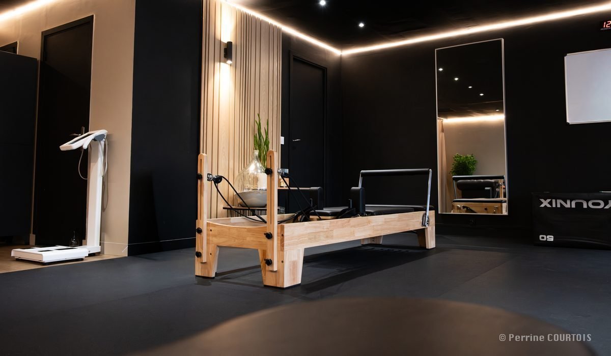 Un studio My Coach : reformer de Pilates, balance d'impédancemétrie, miroir et éclairage indirect au plafond.