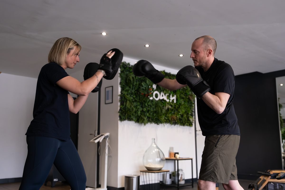 Une coach My Coach tient les pattes d'ours pour un adhérent en gants de boxe, au studio de Marcq-en-Barœul.