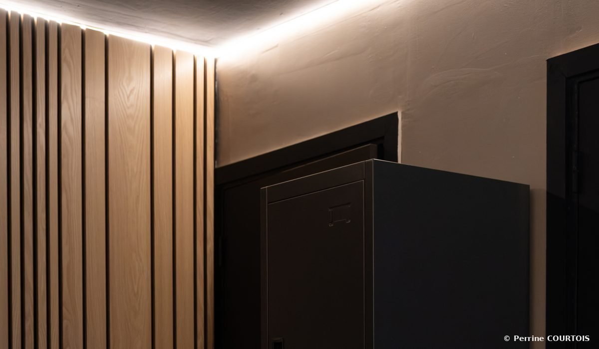 Tasseaux de bois clair et casier sombre sous un éclairage indirect au plafond.