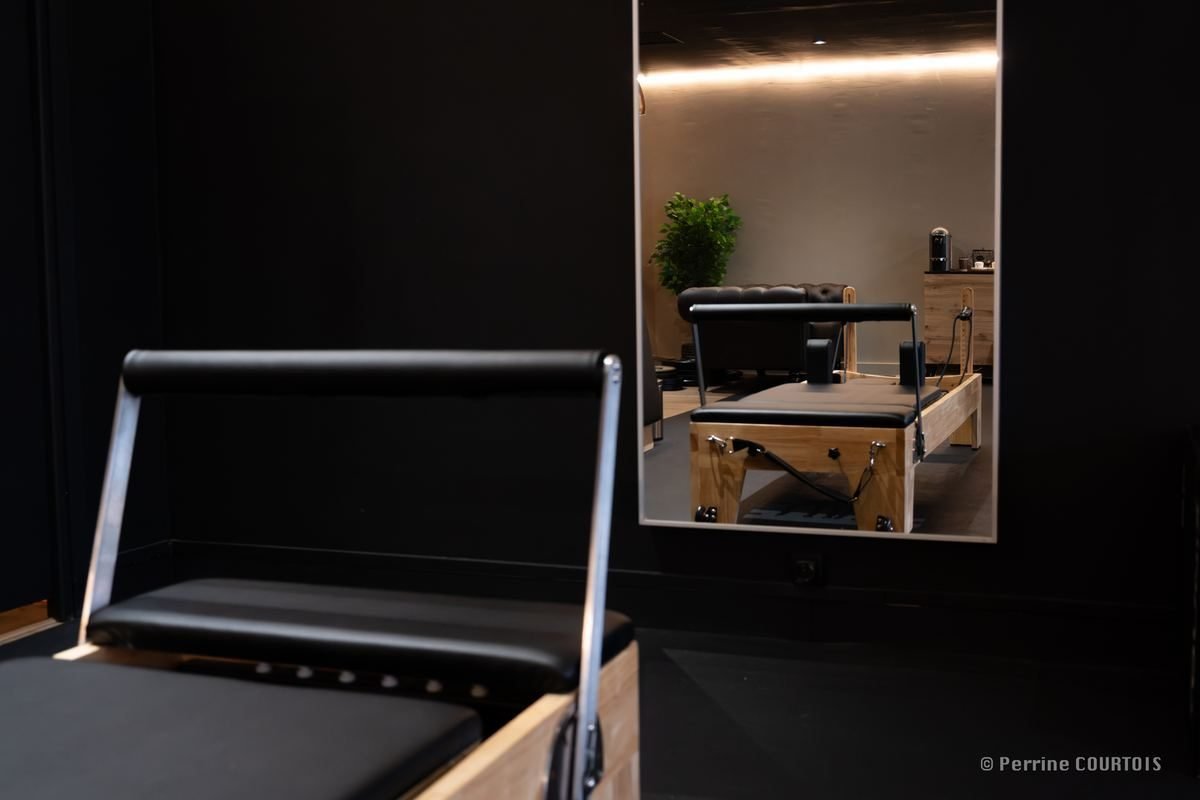 Reformer de Pilates au premier plan, un second reformer se reflétant dans un miroir.