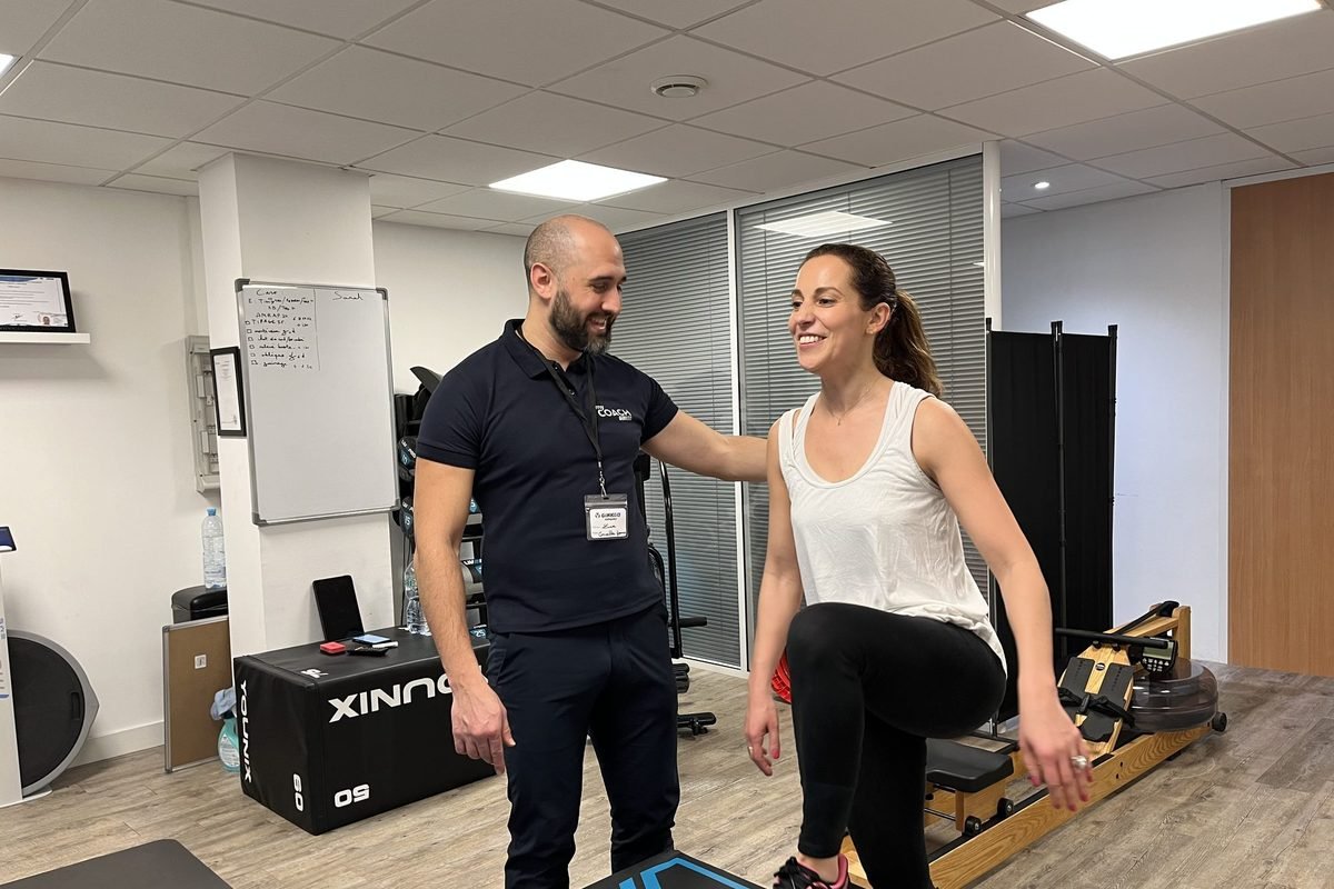 Un coach My Coach accompagne une adhérente souriante pendant un exercice, au studio de Boulogne-Billancourt.