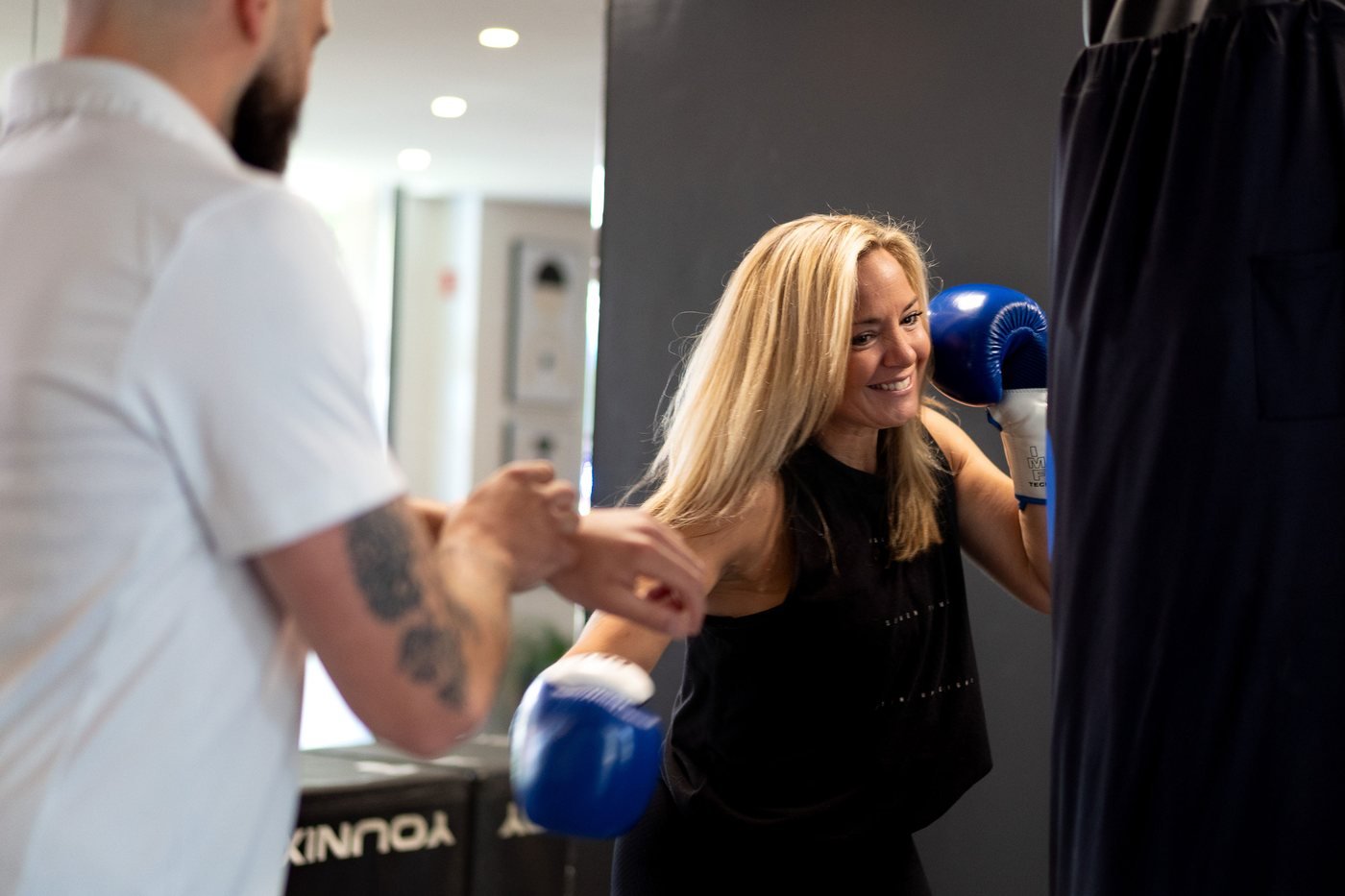 Une coach My Coach guide une adhérente pendant un enchaînement de boxe dans un studio du réseau.