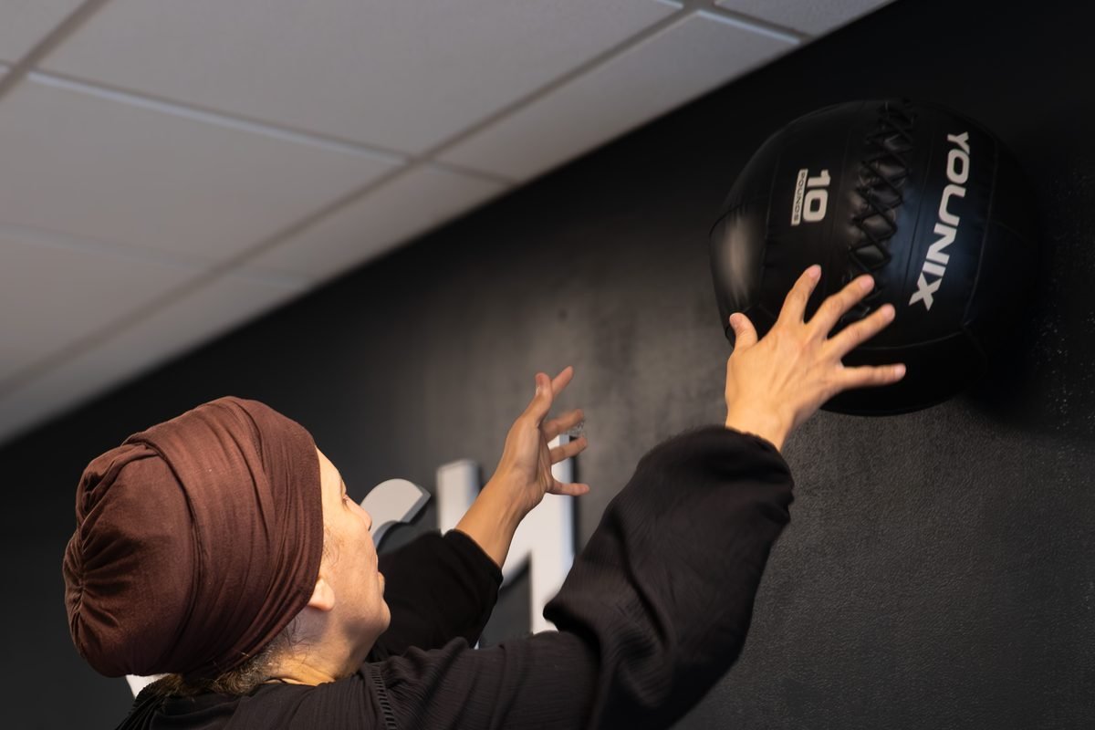Une adhérente lance un médecine-ball contre le mur, au studio de Boulogne-Billancourt.