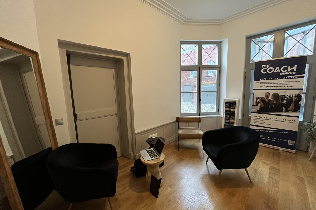L'espace d'accueil du studio de Lille, avec fauteuils, parquet et kakémono My Coach.