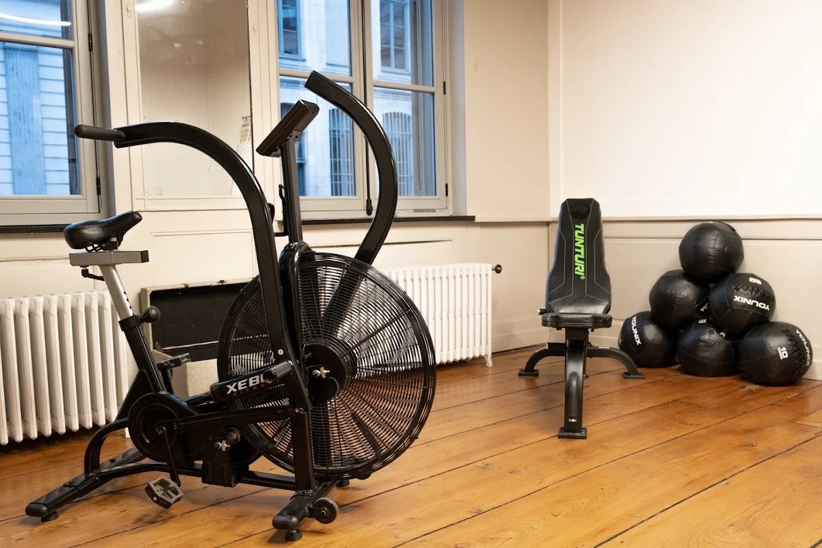 Un vélo à air, un banc de musculation et des médecine-balls dans la salle lumineuse du studio de Lille.