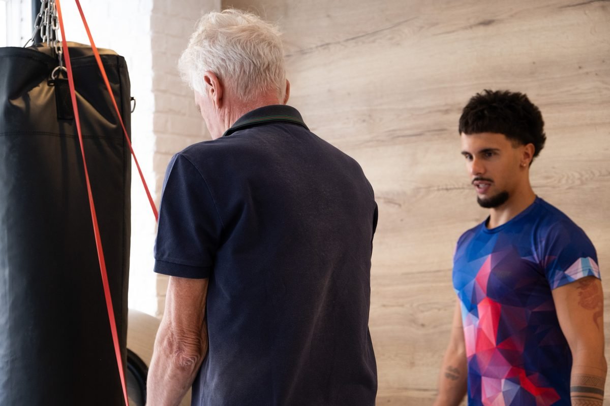 Un coach échange avec un adhérent près du sac de frappe, au studio de Neuilly-sur-Seine.