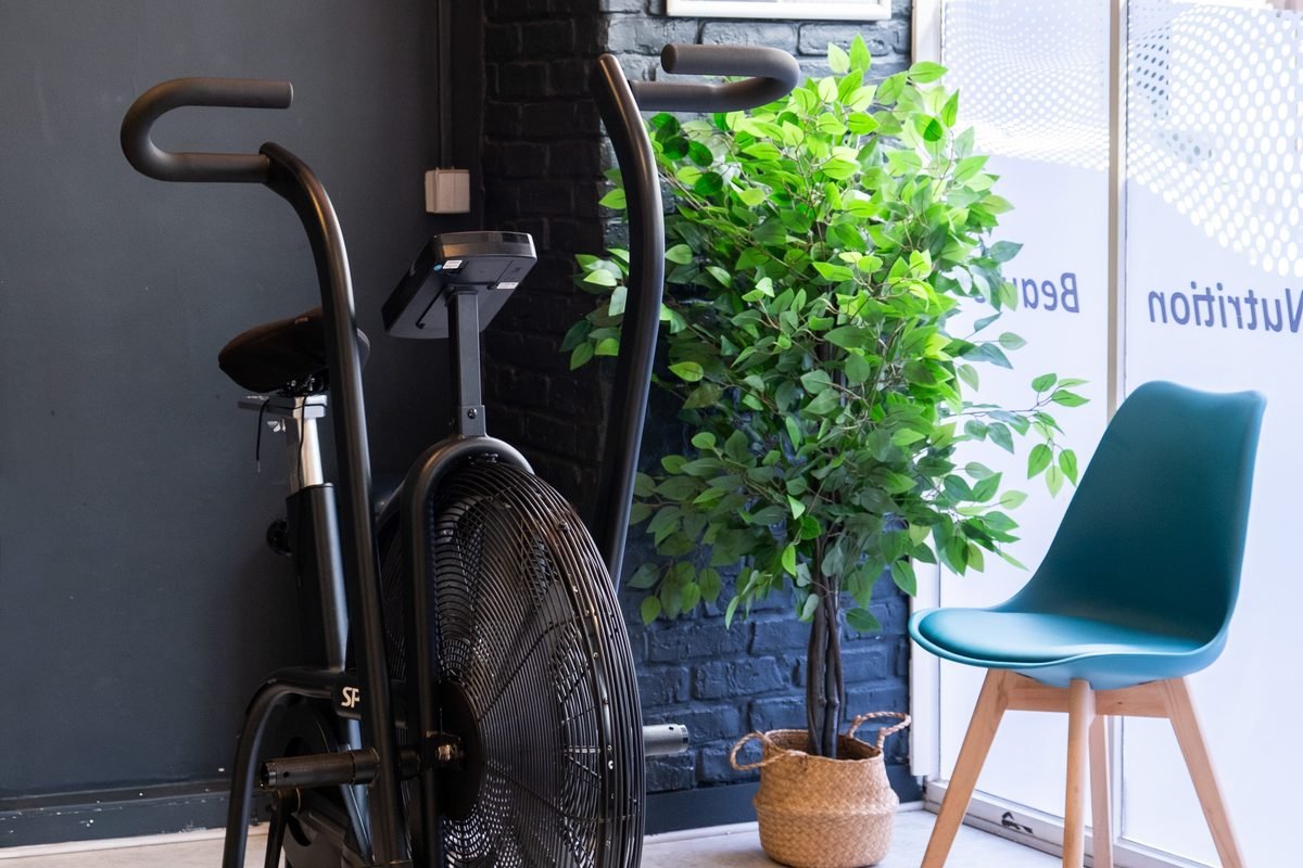 L'entrée lumineuse du studio de Neuilly-sur-Seine, avec un vélo à air et une plante verte.