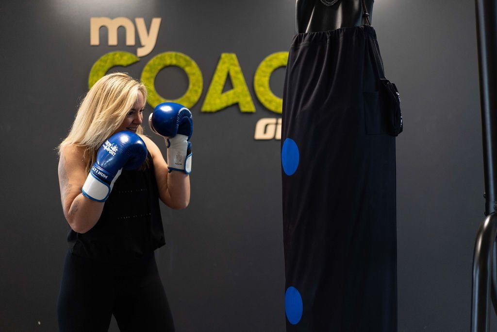 Une adhérente en garde avec des gants de boxe devant le sac de frappe du studio de Wasquehal.