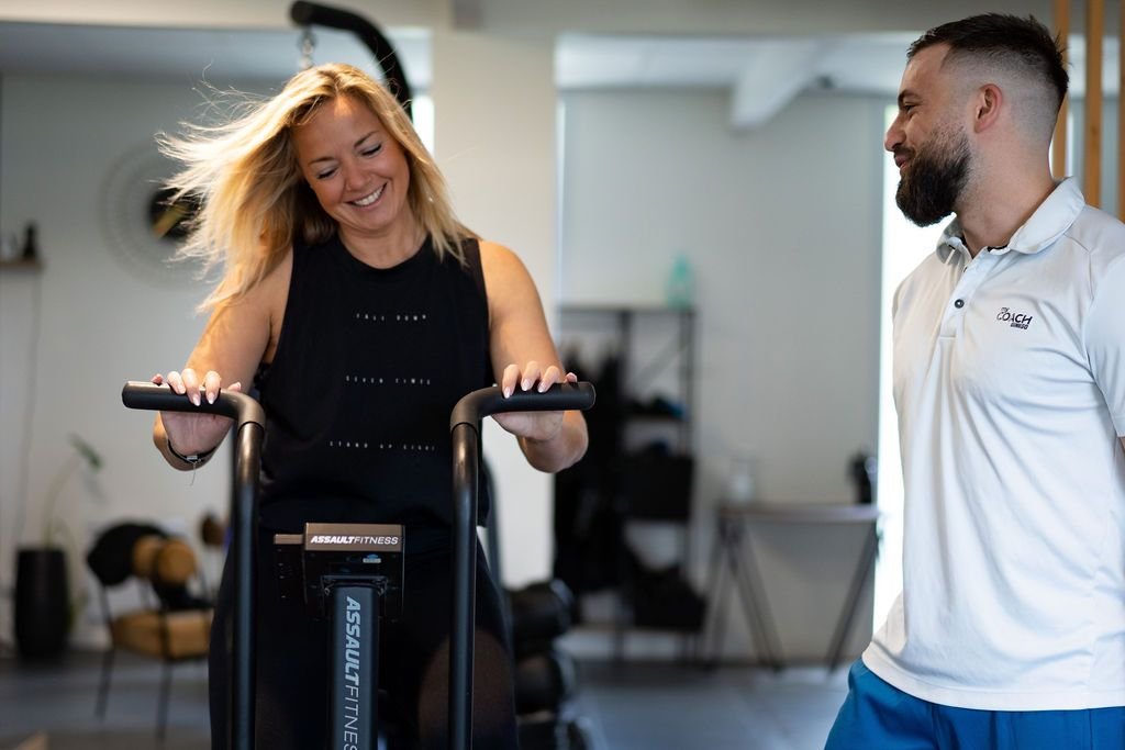Une adhérente sur le vélo à air, encouragée par son coach, au studio de Wasquehal.